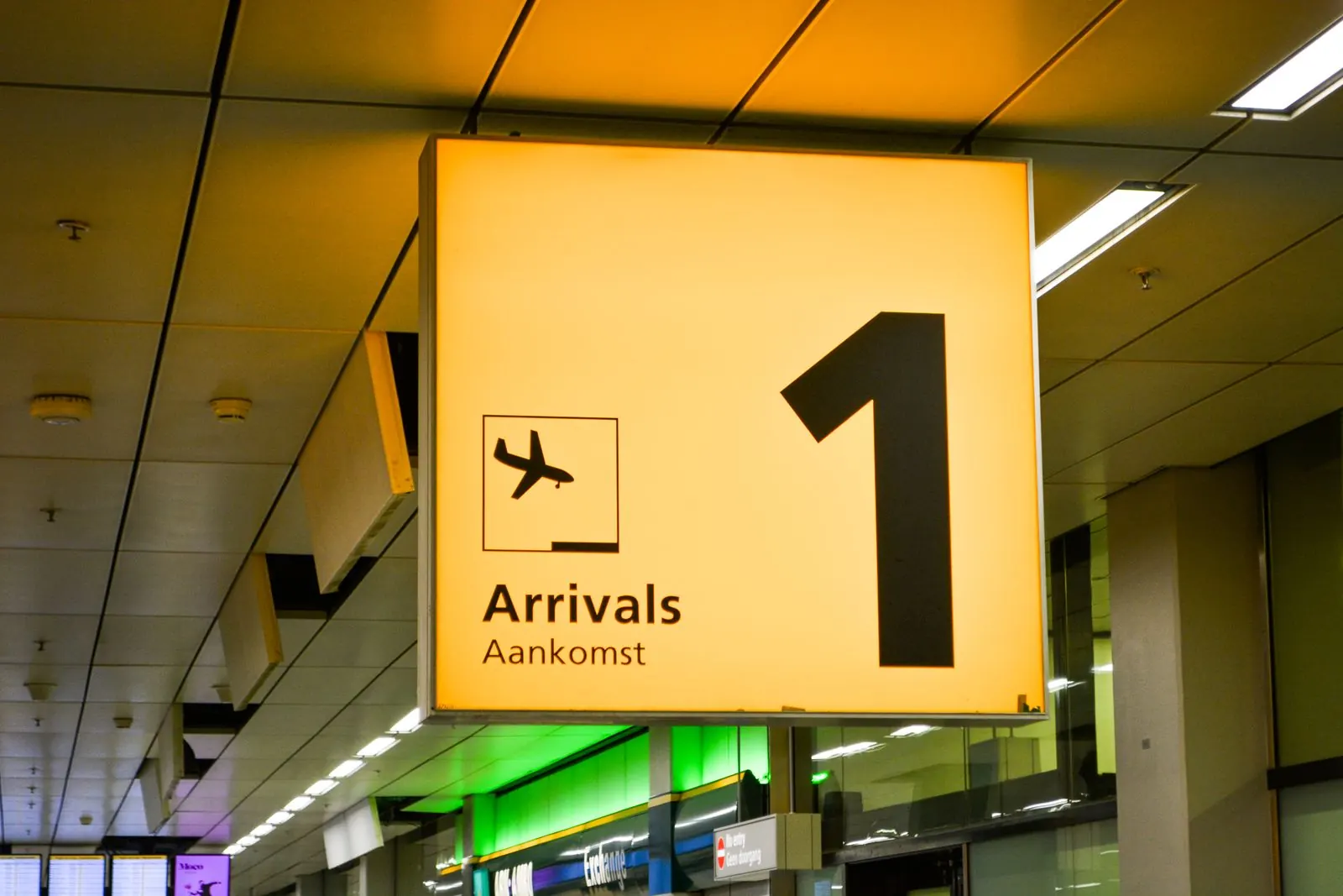 A yellow airport sign reading Arrivals, with the Dutch word Aankomst underneath
